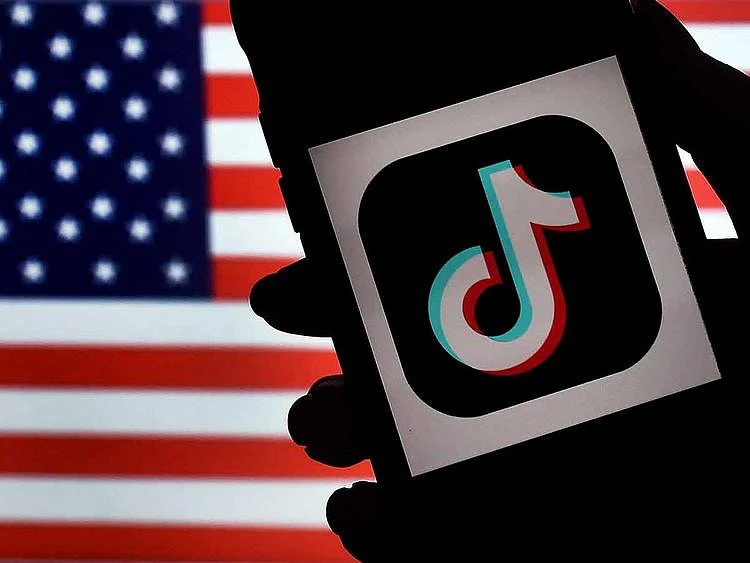 In this photo illustration, the social media application logo, TikTok is displayed on the screen of an iPhone on an US flag background