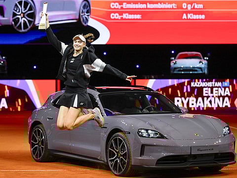Kazakhstan's Elena Rybakina holds her trophy as she jumps in front of her prize, a Porsche Taycan 4S Sport Turismo car, during the victory ceremony at the Women's Tennis Grand Prix WTA tournament in Stuttgart on Sunday.