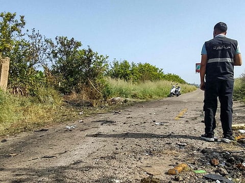 A member of the Lebanese intelligence service stands at the site of an Israeli strike on a vehicle in the Adloun plain area, between Lebanon's southern cities of Sidon and Tyre, on April 23, 2024.  