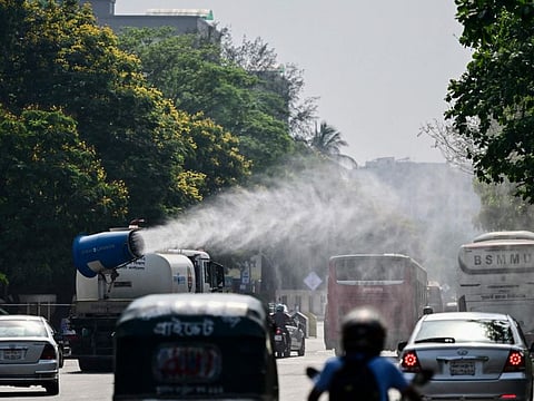 A vehicle of the Dhaka North City Corporation (DNCC) sprays water along a busy road to lower the temperature amidst a heatwave in Dhaka on April 27, 2024.  