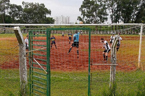 Locals play football in a dirt field in Sao Paulo, Brazil.