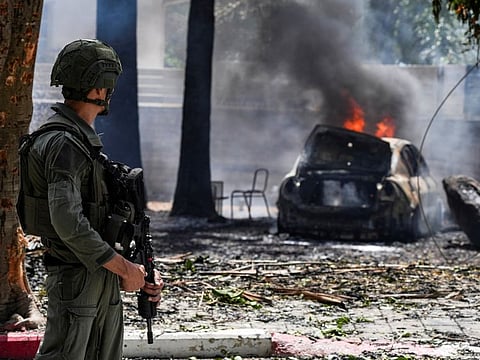 A soldier looks at a burning car at the impact site of a rocket that was fired towards Israel from Lebanon, amid ongoing cross-border hostilities between Hezbollah and Israeli forces, in Kiryat Shmona, northern Israel, on May 5, 2024.  