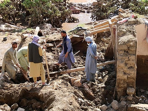 People remove debris from a house damaged by the flood in Firozkoh the capital city of Ghor Province, in Afghanistan on May 18, 2024. 
