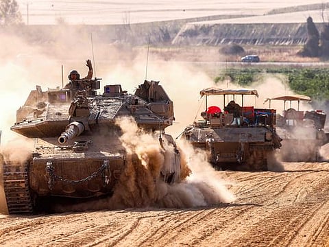 Israeli army battle tanks move near the border with the Gaza Strip at a location in southern Israel.