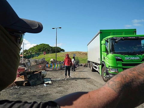 People man a roadblock barricade, with Kanak flags, controlling access to a district in Noumea, France's Pacific territory of New Caledonia, on May 24, 2024. 