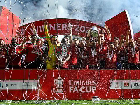 Manchester United's Portuguese midfielder Bruno Fernandes lifts the trophy to celebrate their victory at the end of the English FA Cup final football match against Manchester City at Wembley stadium, in London, on Saturday.