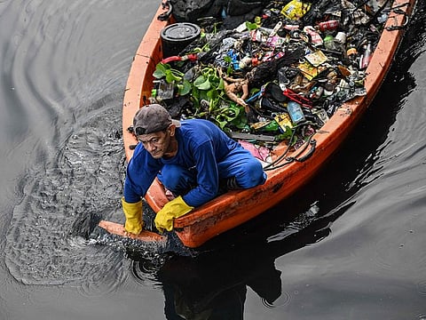 A government worker picks up trash along a river in Paranaque, Metro Manila.