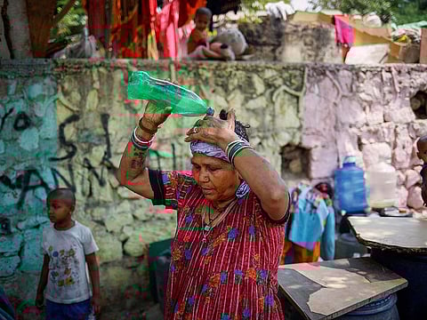 A woman pours water on her head after filling her containers with drinking water from a municipal tanker on a hot summer day in New Delhi, India.