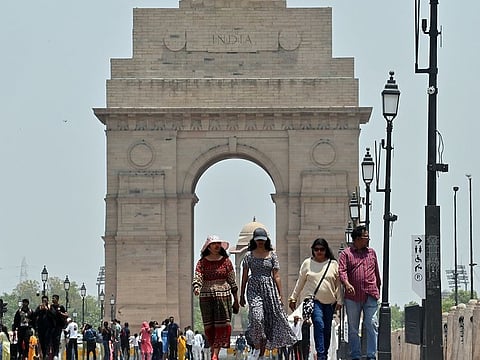 People walk on Kartavya Path near India while covering themselves to protect from the scorching heat on a hot summer day, in New Delhi 