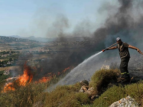 A Lebanese firefighter douses a blaze that swept over fields hit by Israeli shelling in southern Lebanon near the border with Israel, on June 3, 2024, amid ongoing cross-border clashes between Israeli troops and Hezbollah fighters.  