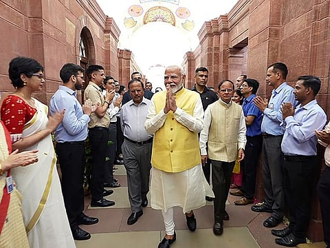 Prime Minister Narendra Modi greets staff as he arrives to assume charge for the third consecutive term, in New Delhi on Monday. 