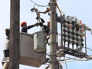 Manila Electric Co (Meralco) linemen repair power meters atop electricity post at the port area of Metro Manila, Philippines.