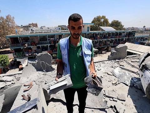 A member of a United Nations investigation team holds large chunks of shrapnel during a visit by investigators of a school run by the UN Relief and Works Agency for Palestine Refugees (UNRWA) which was hit during an Israeli army strike the day before, in the Nuseirat camp in the central Gaza Strip on June 7, 2024.