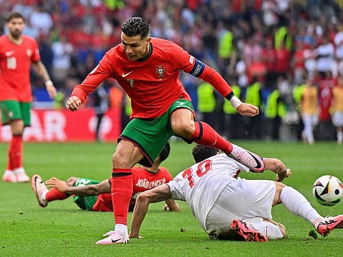 Turkey's midfielder 10 Hakan Calhanoglu fights for the ball with Portugal's forward 07 Cristiano Ronaldo during the UEFA Euro 2024 Group F football match between Turkey and Portugal at the BVB Stadion in Dortmund on June 22, 2024.