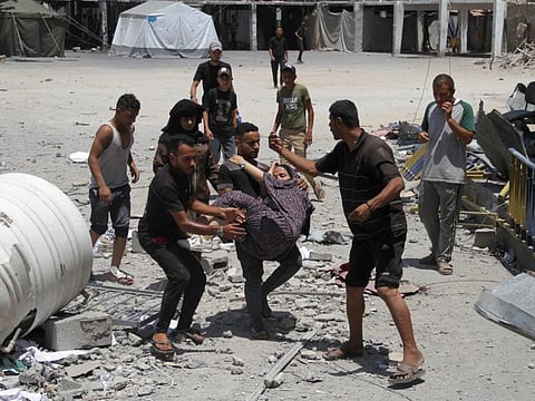 Palestinians carry a casualty outside the headquarters of UNRWA (United Nations Relief and Works Agency) following an Israeli strike, amid the Israel-Hamas conflict, in Gaza City, on June 23, 2024.  