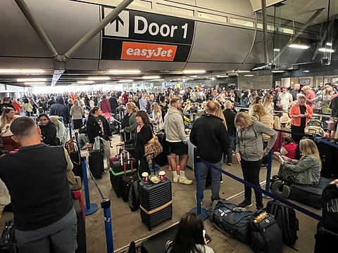 Passengers queue outside Terminal 1 after cancellations at Manchester Airport in  Britain.