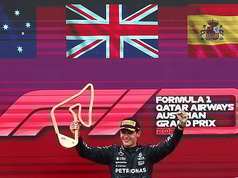 Mercedes' George Russell celebrates with the trophy on the podium after winning the Austrian Grand Prix.