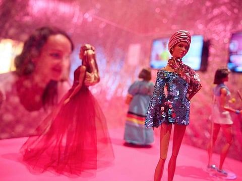 A gallery assistant looks at Barbie dolls from the "Inspiring Women" collection including one of British model Adwoa Aboah during the "Barbie: The Exhibition" photocall at The Design Museum in London on July 1, 2024.  