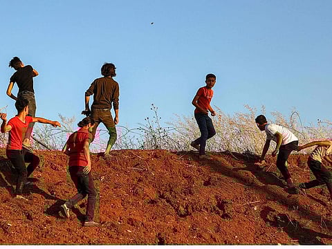 Syrian demonstrators throw stones during clashes as they protest near a Turkish army observation point in Ibbin Samaan in the western part of Syria's northern Aleppo province on July 1, 2024.  