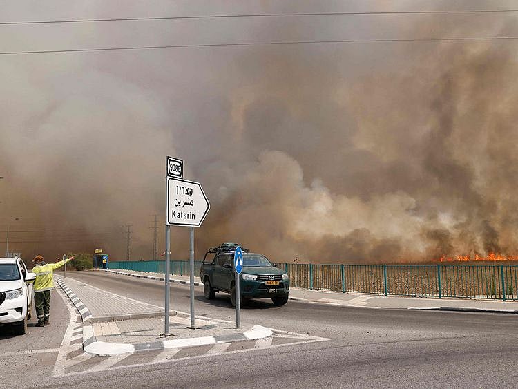  Vehicles leave an area engulfed by smoke from fires after rockets launched from southern Lebanon hit areas in the Israeli-annexed Golan Heights, on July 4, 2024. 