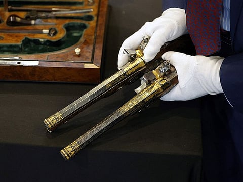 A staff member shows two pistols, which belonged to Emperor Napoleon I, during the preview before their auction.