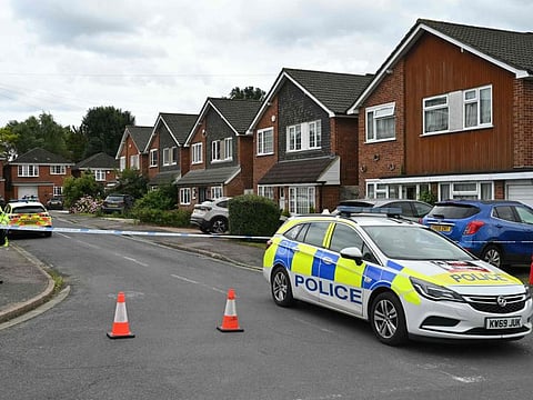 A police officer stands guard behind a cordon at Ashley Close in Bushey in the borough of Hertfordshire, north of London, on July 10, 2024 after a triple "crossbow attack" murder.  
