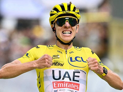 UAE Team Emirates team's Slovenian rider Tadej Pogacar wearing the overall leader's yellow jersey cycles to the finish line to win the 14th stage.