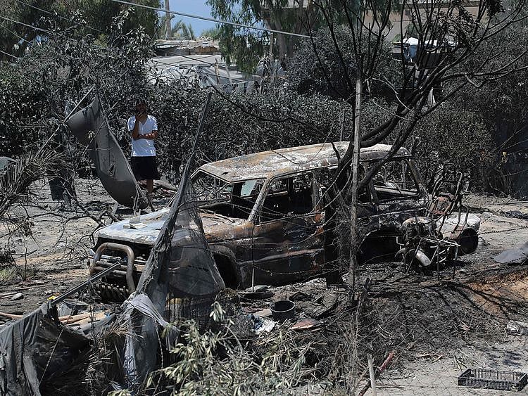 A Palestinian man looks at a burnt out vehicle following an Israeli military strike