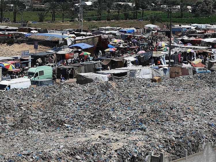 A pile of garbage surrounds a camp for displaced people in Khan Yunis