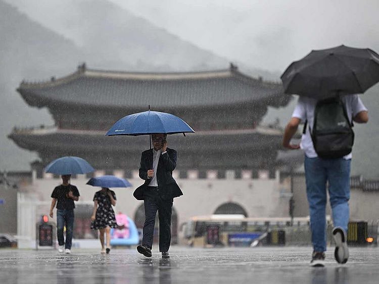 People hold umbrellas as they walk in the central Gwanghwamun square 