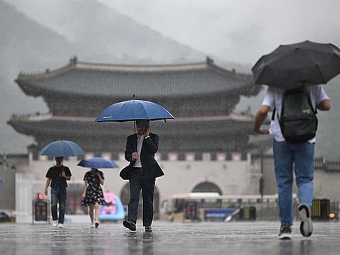 People hold umbrellas as they walk in the central Gwanghwamun square during rainfall in Seoul on July 18, 2024.
