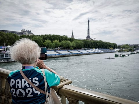A Paris 2024 volunteer takes a picture on the Invalides bridge next to the tribunes set up on the Seine river on the eve of the Paris 2024 Olympic Games opening ceremony in Paris on Thursday.