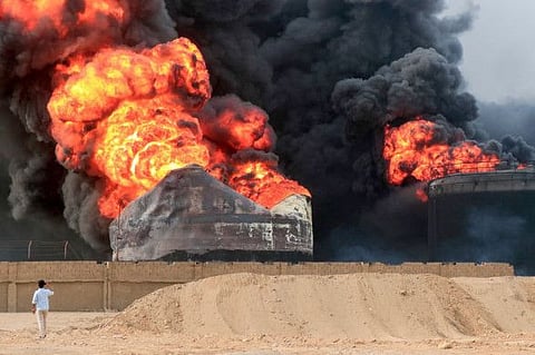 A man takes pictures of a raging fire at oil storage tanks a day after Israeli strikes on the port of Yemen's Al Houthi-held city of Hodeida on July 21, 2024.  