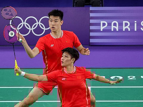 China's Huang Dong Ping (front) hits a shot in her mixed doubles badminton group stage match during the Paris 2024 Olympic Games at Porte de la Chapelle Arena in Paris on July 27, 2024. 