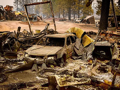 A burned vehicle smolders in the Paynes Creek area of unincorporated Tehama County, California, during the Park fire on July 27, 2024. 