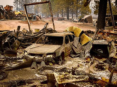 A burned vehicle smolders in the Paynes Creek area of unincorporated Tehama County, California, during the Park fire on July 27, 2024. 