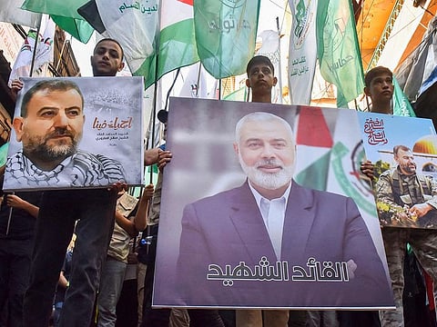 Demonstrators wave flags and hold pictures of the leader of the Hamas group, Ismail Haniyeh, (C) and senior leader Saleh Al Arouri during a protest on July 31, 2024 in Beirut's Burj Al Barajneh camp for Palestinian refugees, denouncing his killing. 