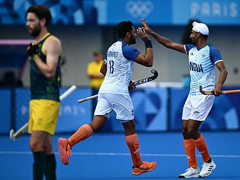 India's Harmanpreet Singh celebrates with a teammate after scoring his team's third goal in the men's pool B match against Australia on Friday.