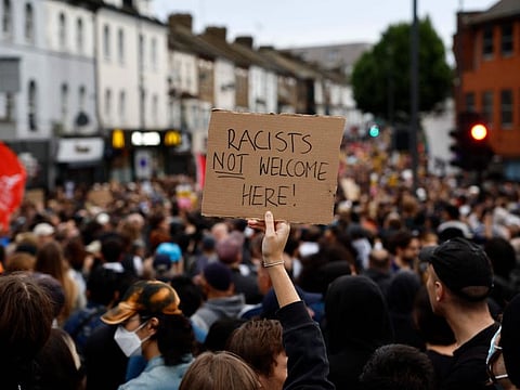 A protester holds a placard reading "Racists not welcome here" during a counter demonstration against an anti-immigration protest called by far-right activists in the Walthamstow suburb of London on August 7, 2024.  
