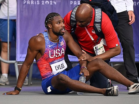Bronze medallist US' Noah Lyles (C) receives medical attention after competing in the men's 200m final of the athletics event.