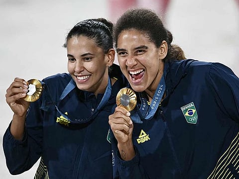 Gold medallists Eduarda Santos Lisboa (L) and Brazil's Ana Patricia Silva Ramos pose with their medals on the podium for the victory ceremony of the women's beach volleyball event during the Paris 2024 Olympic Games at the Eiffel Tower Stadium in Paris on August 9, 2024. 