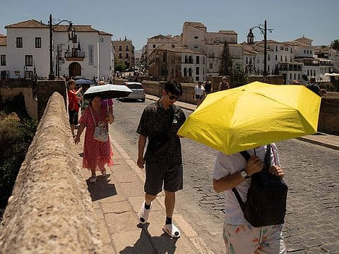 Tourist hide from the sun with umbrellas as their visit Ronda, southern Spain as the country faces the fourth heatwave of the summer, on August 9, 2024. (Photo by JORGE GUERRERO / AFP)