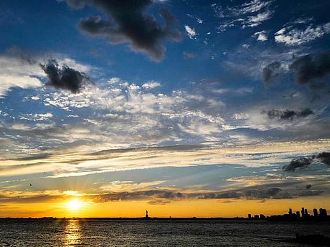 The sun sets behind the Statue of Liberty in New York City. [Illustrative imge]