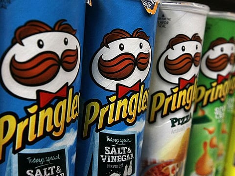 Packages of Pringles potato chips are displayed on a shelf at a market. 
