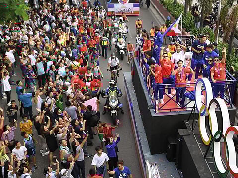 Double gold medalist Philippines' Carlos Yulo and other athletes who competed at Paris 2024 Olympics, wave from a float during a celebratory homecoming parade along a street in Manila on Wednesday.