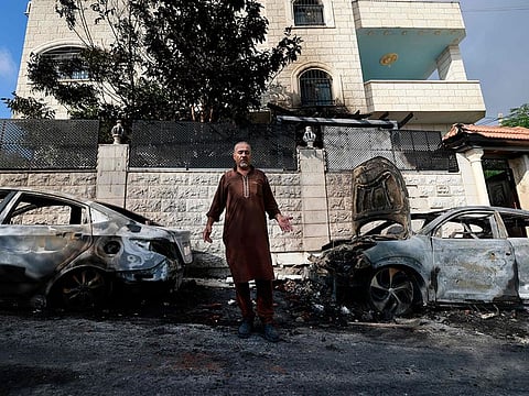 A man stands in front of burnt cars, a day after an attack by Jewish settlers on the village of Jit near Nablus in the occupied West Bank that left a 23-year-old man dead and others with critical gunshot wounds, on August 16, 2024.  