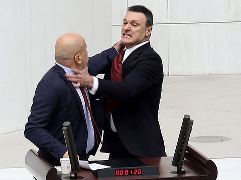 Former Turkish football player and deputy of ruling AKP (Justice and Development Party) Alpay Ozalan (R) scuffles with Turksih Workers Party (TIP) deputy Ahmet Sik (L) at Grand National Assembly of Turkey in Ankara on August 16, 2024. 
