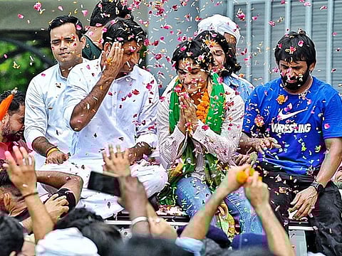 Wrestler Vinesh Phogat accompanied by Congress MP Deepender Singh Hooda and wrestler Bajrang Punia greet the people as she arrives at IGI Airport following the Paris 2024 Olympic games, in New Delhi on Saturday