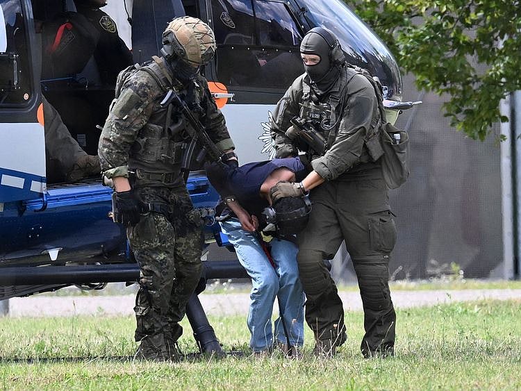 Members of a special police unit escort a man suspected to be responsible for the Solingen knife attack from a helicopter to the office of the Federal Prosecutor in Karlsruhe, southern Germany, on August 25, 2024.