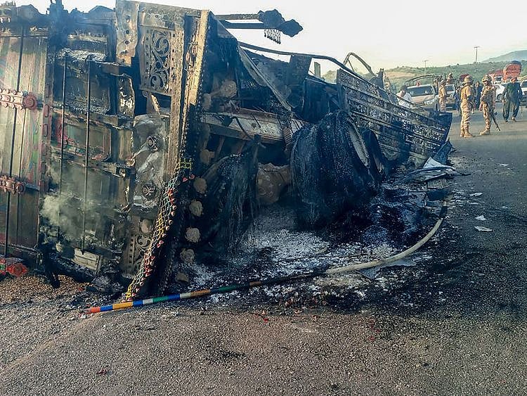 Security personnel stand guard near the charred vehicle at the shooting site on the national highway in Musakhail district, Balochistan province on August 26, 2024.  